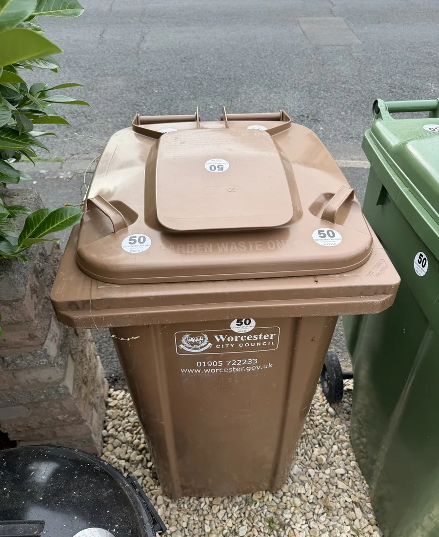 Brown recycling bin with round address stickers on the lid and front