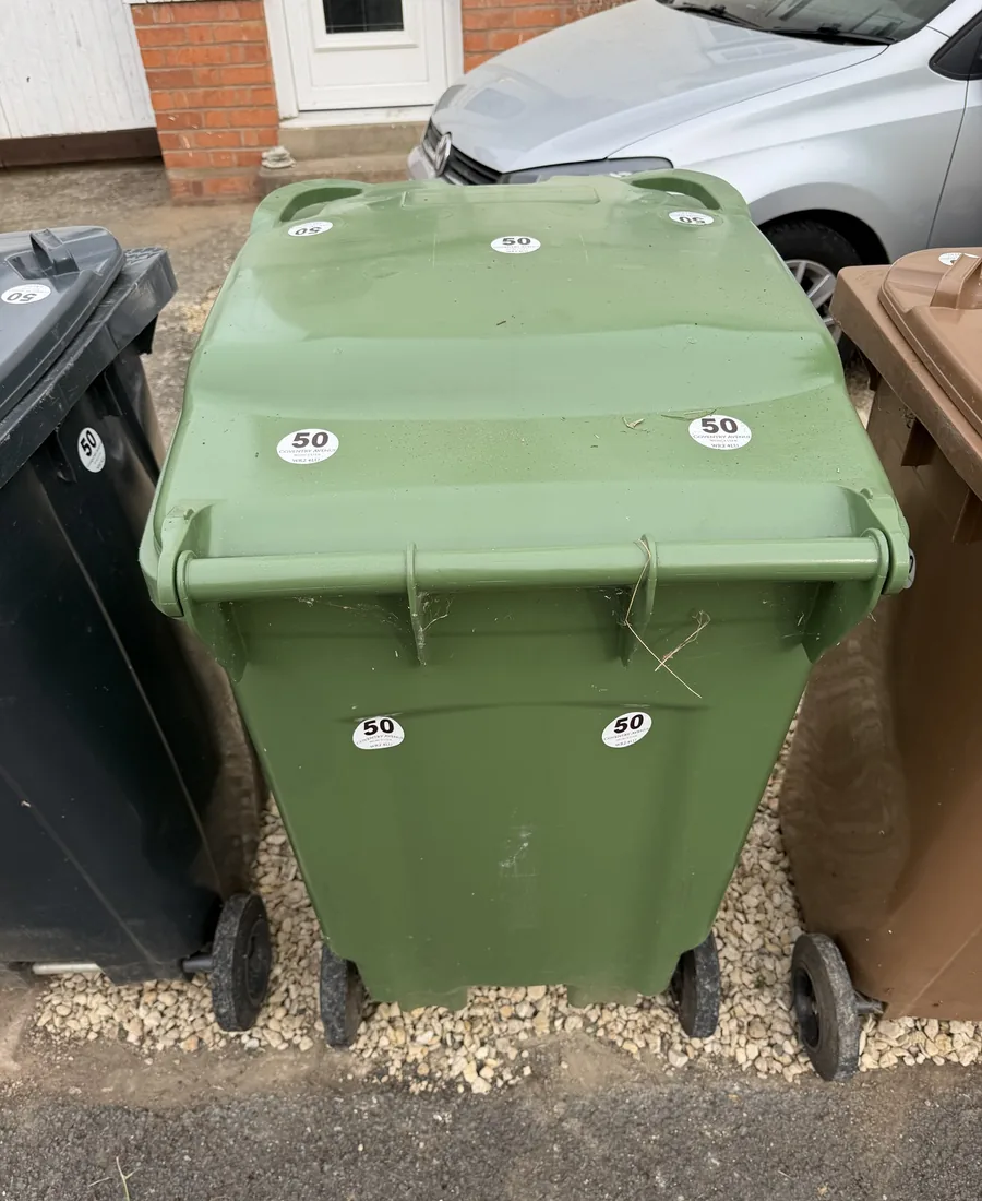 Green garden waste bin with round address stickers on the lid and front